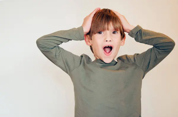 stock image Surprise, portrait and child in home with wow, happy and crazy emoji gesture by white wall. Young boy, good news and gossip and excited with open mouth, omg and mind blown from deal announcement.