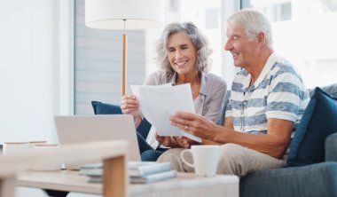 Paperwork, old couple and reading for retirement, house and financial report of senior people and planning. Happy, laptop and investment of fund, online and documents for pension in lounge of home.