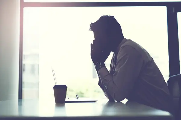 stock image Stress, desk and man in office, thinking and frustrated with financial fraud of company and morning. Business, accountant and anxious for criminal charges, contemplating and headache for person.