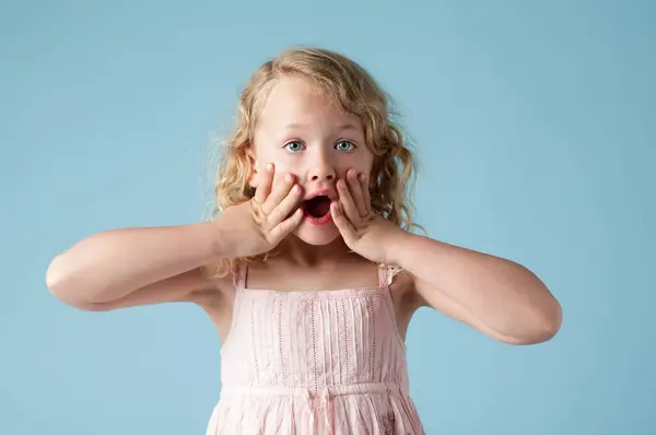 stock image Studio, little girl and portrait with wow for surprise, expression and isolated on blue background. Model, backdrop and kid for announcement with hand on face, reaction and shocked with mind blown.