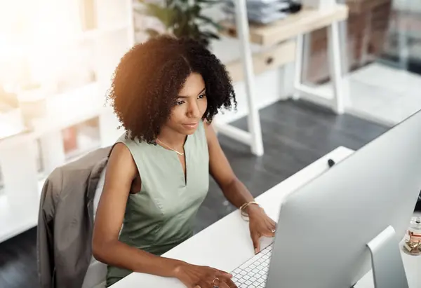 stock image African business woman, smile and computer in office for career, online digital report and web project. Editor or young person with tech and looking at screen for typing or internet with lens flare.