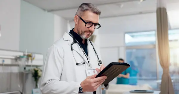 stock image Medical, doctor and typing on tablet at clinic for Telehealth consultation, healthcare charts and health records. Man, digital and surgery schedule, prescription information and treatment compliance.