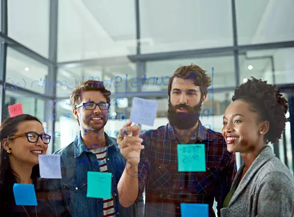 stock image Team, brainstorming and notes on glass in office for schedule or daily routine for tasks or targets. Employees, window and creative designers looking on calendar for projects, timelines and goals