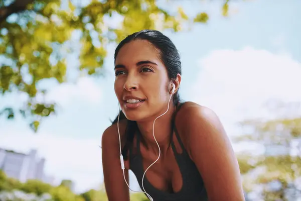 stock image Fitness, rest and woman in park with earphones for exercise, marathon training and running for wellness. Sports, music and person breathe listening to workout playlist, audio and radio for health.