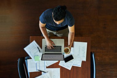 Business man, laptop and above with documents, typing or reading charts on screen for finance. Person, computer and paperwork for accounting, graphs or stats for review with coffee at office in Italy. clipart