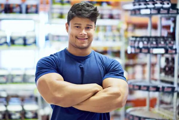 Fitness, man and portrait in store for supplements, vitamins and product for muscle development. Retail shop, male person or bodybuilder with arms crossed for customer service, nutrition and diet.