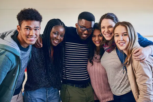 Students, group and hug in portrait with smile, diversity and support for education, development and solidarity. Men, women and friends at university, embrace and studying for scholarship in Canada.