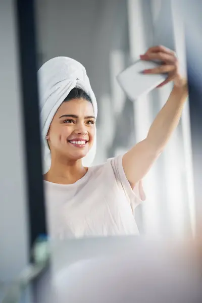 stock image Woman, happy and reflection with selfie in bathroom for skincare, routine and social media update. Cosmetics, influencer and towel with digital photography in home for online, dermatology and post.