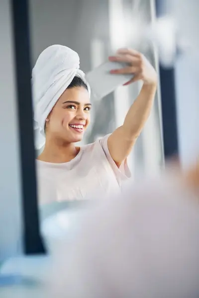 stock image Woman, happy and mirror with selfie in home for skincare, morning routine and social media update. Cosmetics, influencer and towel with digital photography in bathroom for online, post or dermatology.