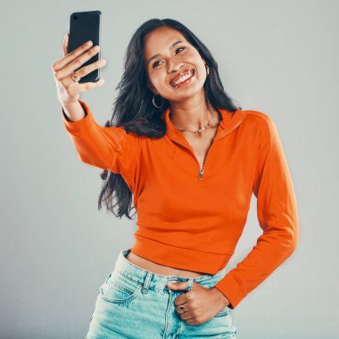 Influencer, selfie or happy woman with fashion in studio for vlogging, social media or blog by gray background. Smile, model and girl taking picture for photography and post online for trendy style. clipart