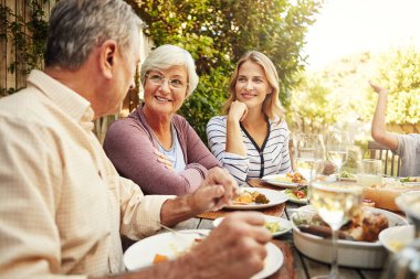 Garden, lunch and mother with senior parents in backyard for brunch, supper and eating together. Family, happy and people at table with food for bonding at Thanksgiving, Christmas and festive party. clipart