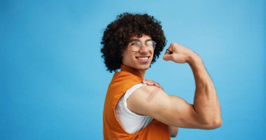 Studio, man and flex with bandage after vaccine, medical treatment and prevention of flu disease. Mockup space, male person or portrait with plaster for healthcare, virus awareness or blue background. clipart