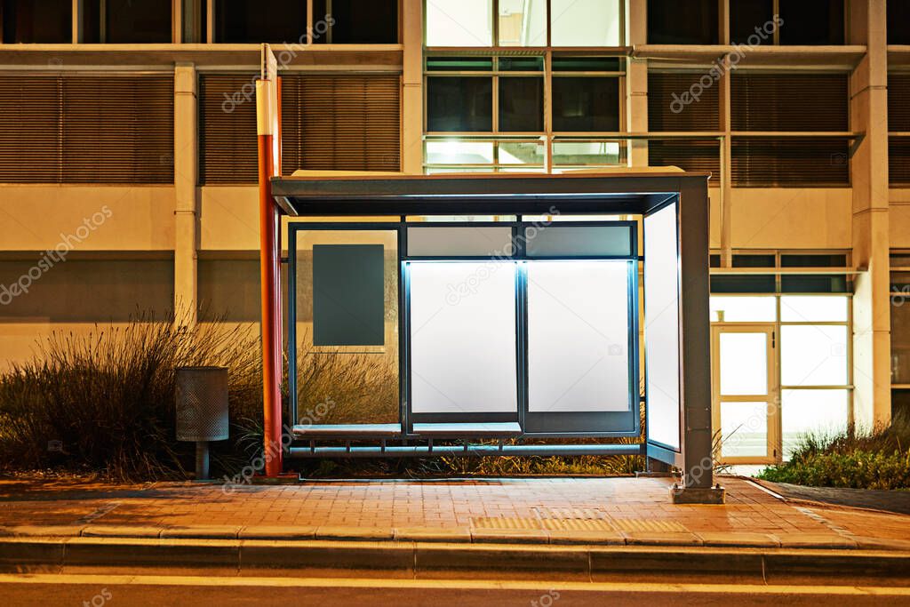 Road sign, billboard and night with bus stop or mockup space for advertising, message or notification in city. Empty poster, banner or post for brand, logo or marketing on sidewalk in late evening.
