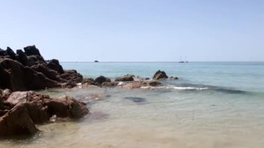 St. Brelade, Jersey, Channel Adaları 'ndaki kumlu bir sahilde dalgalar ağır çekimde kırılıyor..