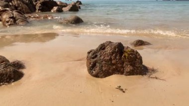 St. Brelade, Jersey, Channel Adaları 'ndaki kumlu bir sahilde dalgalar ağır çekimde kırılıyor..