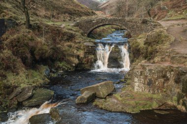 Şelalenin kırsal bir manzarası ve Tepe Bölgesi Ulusal Parkı 'ndaki Three Shires Head' deki yük atı taş köprüsü..