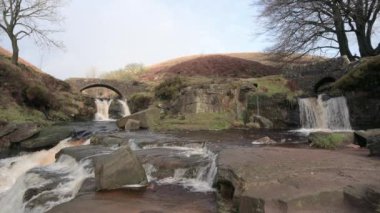 İngiltere 'nin Peak District Ulusal Parkı' ndaki Three Shires Head 'de şelalenin ve yük taşı köprüsünün kırsal bir kış manzarasının çekimleri yapılıyor..