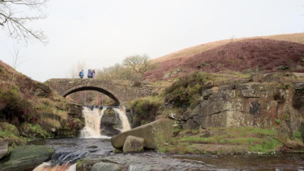 Rural Winter Landscape Scene Hikers Crossing Waterfall Packhorse Stone Bridge — Stock Video
