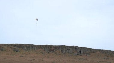 Kış boyunca Derbyshire Tepesi Ulusal Parkı 'ndaki Stanage Edge' de paragliding.