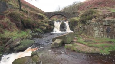 Kırsal bir kış manzarasından uzaklaşın şelalenin ve Three Shires Head 'in taştan köprüsünün İngiltere, İngiltere' deki Peak District Ulusal Parkı 'ndaki şelalesinden uzaklaşın..