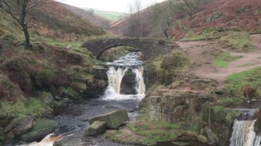 Kırsal bir kış manzarasından uzaklaşın şelalenin ve Three Shires Head 'in taştan köprüsünün İngiltere, İngiltere' deki Peak District Ulusal Parkı 'ndaki şelalesinden uzaklaşın..
