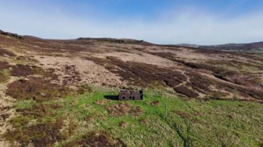 Staffordshire, İngiltere 'deki The Peak District Ulusal Parkı' ndaki Hamamböcekleri 'nde terk edilmiş bir çiftlik binasının üzerinde uçan sinematik hava aracı görüntüleri..