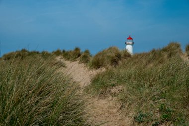 The sand dunes, and the grade II listed building Point of Ayr Lighthouse at Talacre beach in North Wales, UK on a sunny summer day. clipart