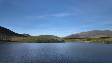 Motion lapse of a boat docking at the boat house at Llyn y Dywarchen with Yr Wyddfa in the background in the Eryri National Park, Wales, UK.