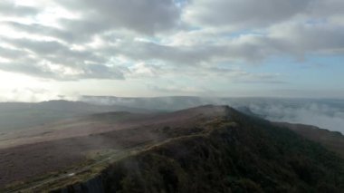 İngiltere, İngiltere 'deki Peak District Ulusal Parkı' nda serpilmiş mor fundanın üzerinde uçan sinematik bir B rulo film..