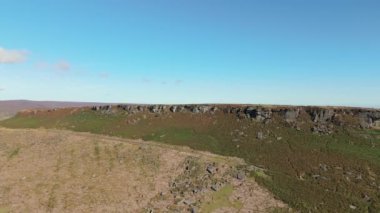 Stanage Edge 'in İngiltere, İngiltere' deki Peak District Ulusal Parkı 'ndaki kumtaşı yamaçlarının sinema insansız hava aracı dönüşü..
