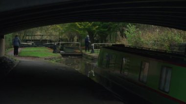 STOKE-ON-TRENT, STAFFORDSHIRE, ENGLAND - 30 EKİM 2024: Caldon Kanalı 'nda kilit açan erkek ve kadın bir çocuk dar kayık dizisi 3' ün 2 'sini kullanırken.
