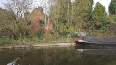 FROGHALL, STAFFORDSHIRE, ENGLAND - 11 Kasım 2024: Harabe bir ev ve Froghall Rıhtımı yakınlarındaki eski harap tekne tarafından Caldon Kanalı 'na demirlenmiş dar bot.