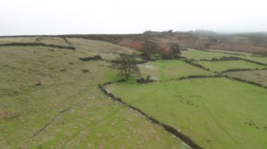 Terk edilmiş bir çiftlik binasında hızlı bir uçuşun ve İngiltere 'nin Peak District bölgesindeki Roach End' de hafif kar tozu eşliğinde kışın bataklık arazisinin sinematik insansız hava aracı görüntüleri..