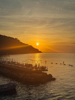 Bir grup insanla birlikte iskelede gün batımı.