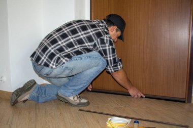 Tamirci evin kapısına toz mühürü takıyor. Daha iyi termal yalıtım ve zemin temizliği.