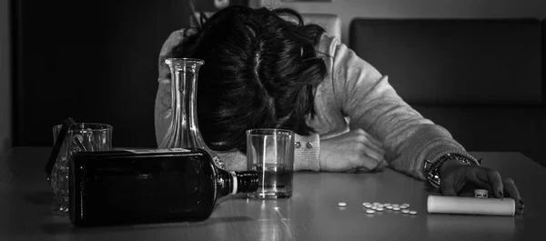 Image of a young woman passed out on the table after abusing alcohol and psychotropic drugs. Reference to the abuse and dependence of these substances. Horizontal banner