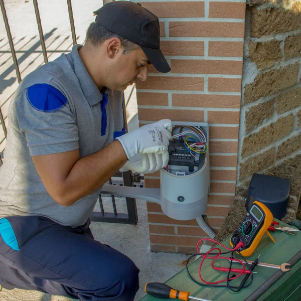 Expert in automatic systems while repairing the electronic card of a gate. Technician repairing and installing the motor of an automatic driveway gate.