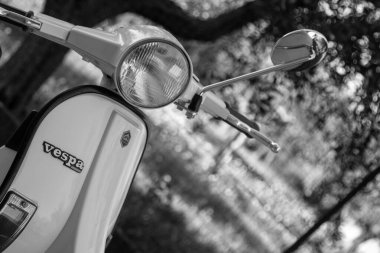 Close-up image of an old white colored Piaggio Vespa motorcycle.