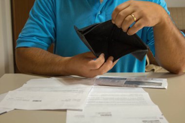 Masanın üzerinde bir sürü banknot olan, parasız, cüzdanı açık bir adam resmi. Mevcut ekonomik ve mali kriz. 