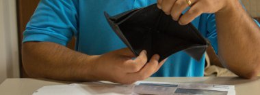 Masanın üzerinde bir sürü banknot olan, parasız, cüzdanı açık bir adam resmi. Mevcut ekonomik ve mali kriz. Yatay Pankart 