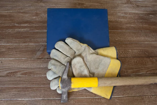 Image of a first aid kit a pair of work gloves and a mason\'s hammer. Reference to accidents at work.