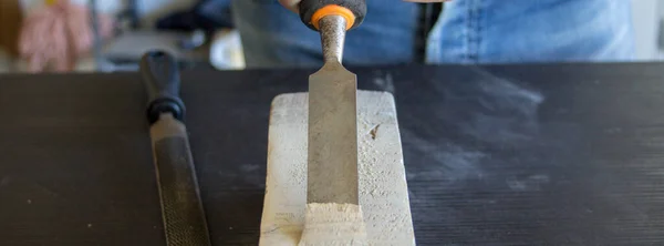 Image of a handyman craftsman's hands holding a carpenter's hammer and chisel while doing some work and carving on wood. DIY work in the laboratory. Horizontal banner