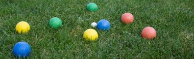 Image of colored bowls on a green lawn during a match. Horizontal banner 