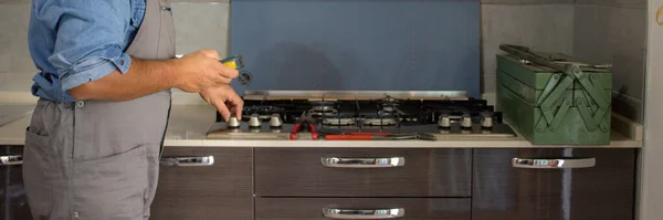 Image of a handyman technician who with a detector carries out checks in a kitchen for safety and gas leaks from the stove. Prevention and safety at home. Horizontal banner