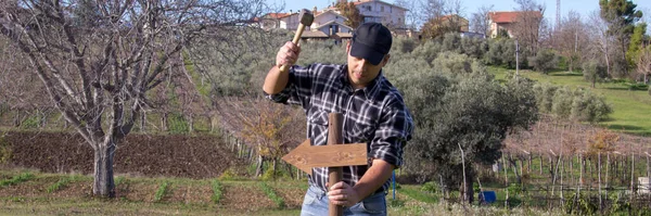 stock image Image of a man driving a stake with an arrow into the ground with a hammer. Pole indicating the direction to take. Horizontal banner 