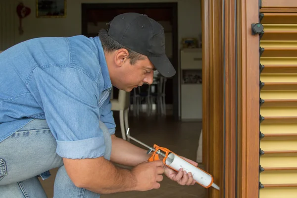 stock image  Image of a handyman who with a silicone gun closes the cracks in the window. Improve the insulation, energy and thermal efficiency of the house