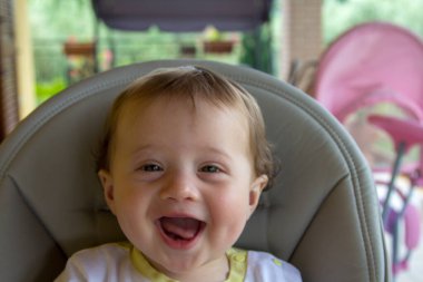 Yükseklerde oturan sevimli gülümseyen yeni doğmuş bebek görüntüsü.