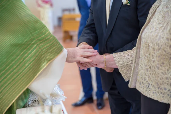 Image of the hands of an elderly couple celebrating 50 years of marriage while the parish priest gives them the blessing.