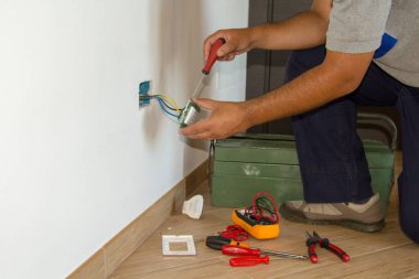 Tamirci bir elektrikçinin ev elektrik prizini tamir edip monte edişinin resmi. DIY güç dolgusu çalışır.