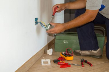 Tamirci bir elektrikçinin ev elektrik prizini tamir edip monte edişinin resmi. DIY güç dolgusu çalışır.